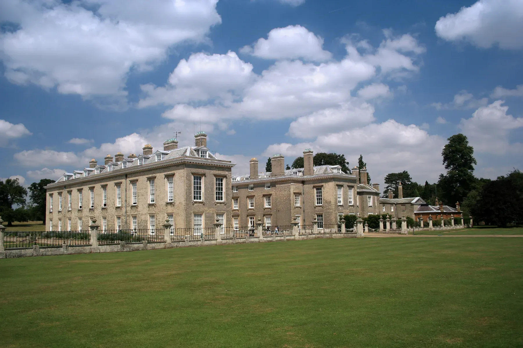 The long frontage of Althorp House across its lawn under a summer sky