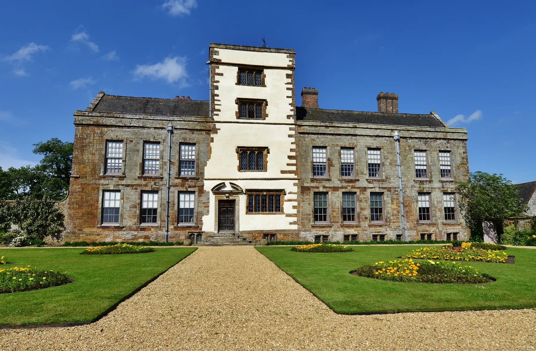 The Elizabethan front of Canons Ashby House with its gravel path and flower beds