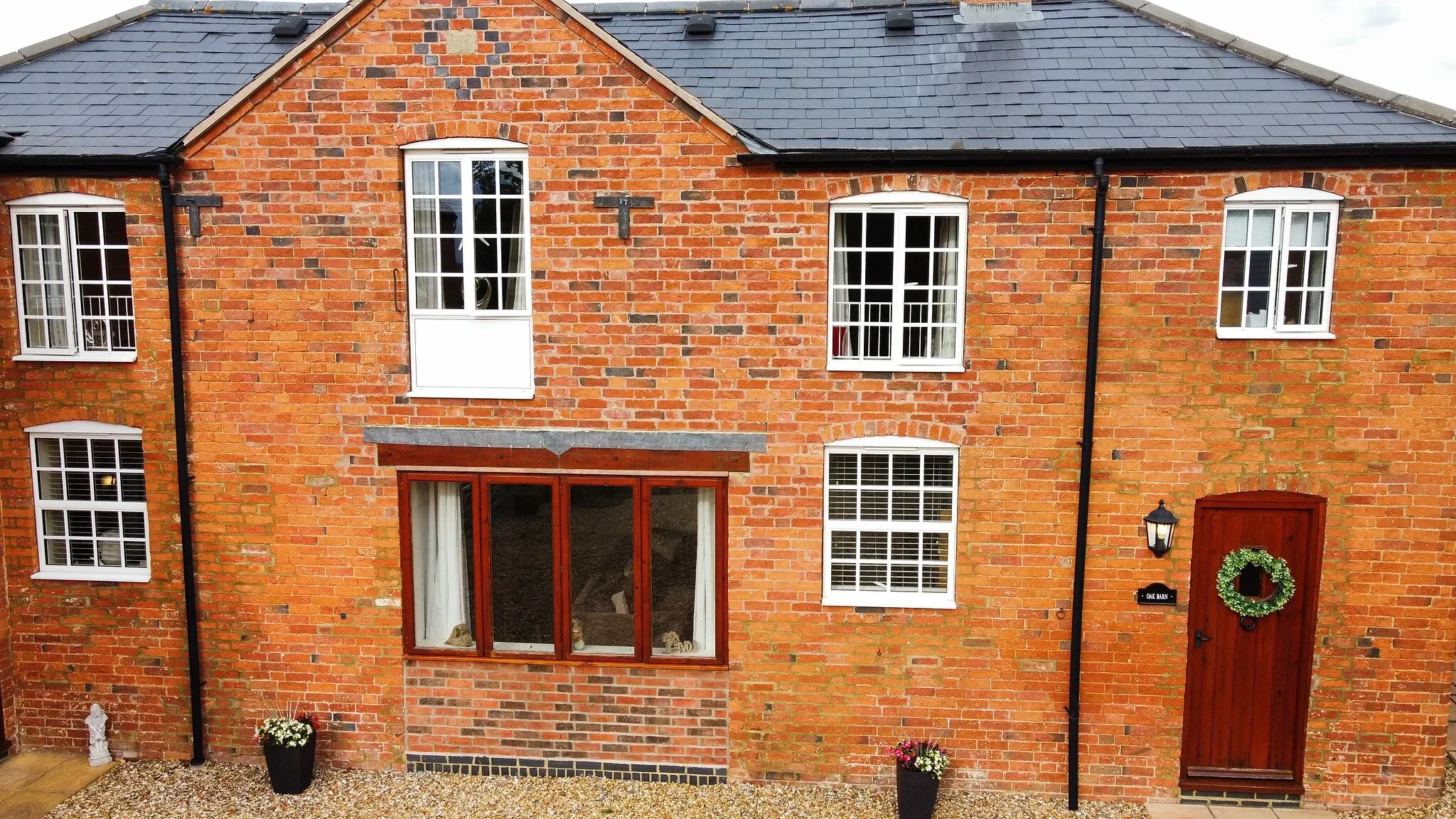 The red brick frontage of Oak Barn with its name plate and wreath on the door