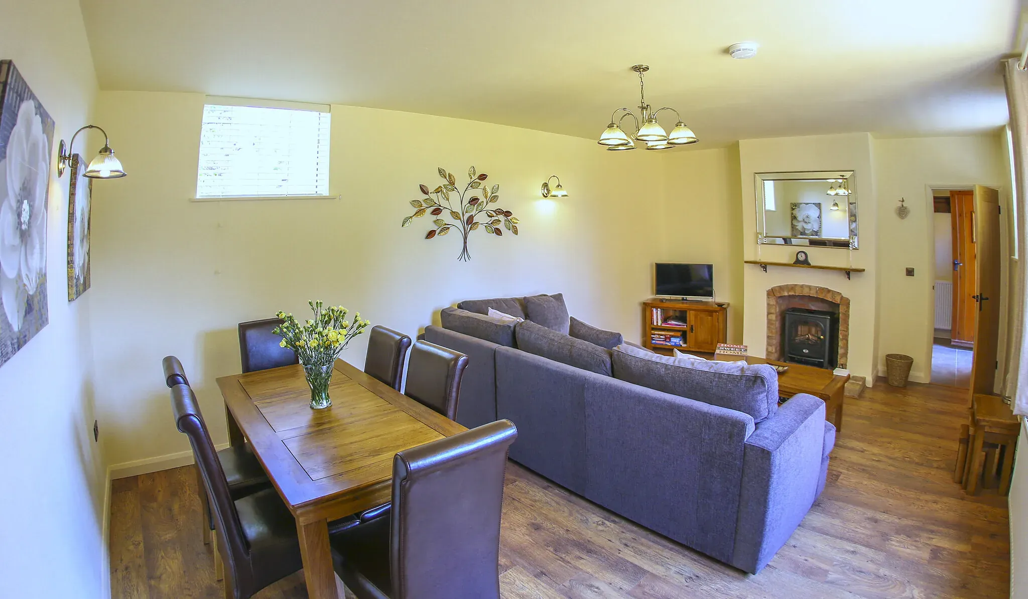 Oak Barn lounge-diner with grey corner sofa, brick fireplace and an oak table laid for six
